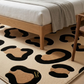 Beige rug with black abstract patterns in a room with wooden furniture.