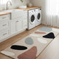Colorful geometric rug on a wooden floor in a kitchen with washing machines.