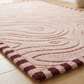 Pink textured rug with wavy pattern on a wooden floor