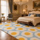 A large area rug with a light blue and white wavy pattern and yellow circular accents, styled in a luxurious, ornate bedroom with gold furniture and a crystal chandelier.