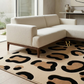 Beige sectional sofa in a living room with a patterned rug.
