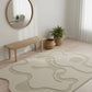 Modern interior with a round mirror, wooden bench, and abstract rug on a light wood floor.