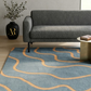 Living room with a gray sofa, blue rug with orange lines, and a black vase with greenery.