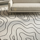 Patterned carpet with wavy lines in a room with a sofa.
