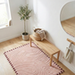 Nest living room with pink rug, wooden bench, and plant