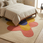 Colorful abstract rug on a wooden floor with a bed in the background