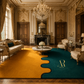 A luxury living room featuring a large, wavy-split area rug in mustard yellow and deep teal. The room is styled in an elegant, classic French Chantilly tradition with gold-trimmed walls, a crystal chandelier, a marble coffee table, and matching cream-colored sofas.