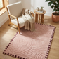 Pink textured rug with a wooden chair and small table in a room with natural light.