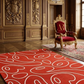 Red and white patterned rug in a luxurious room with ornate walls and a gold chair.