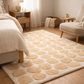 Beige patterned rug in a bedroom with bed, nightstand, and chair.