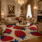 A luxurious living room featuring a large cream-colored area rug with a bold red and blue strawberry pattern. The room is styled in an opulent, classic European chateau setting with gold-trimmed furniture, a crystal chandelier, and ornate wall art.