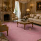 A luxurious pink area rug with a subtle wavy geometric pattern and a gold monogram logo, styled in an elegant, ornate vintage living room with gold furniture and a marble fireplace.