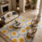 A large area rug with a retro daisy pattern in light blue, cream, and mustard yellow, styled in a luxurious, high-end living room with a cream sofa, two armchairs, and a marble coffee table.