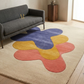 Colorful abstract rug on a wooden floor with a gray sofa in a room.
