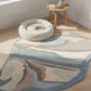 Round rug with abstract pattern on a wooden floor, next to a small round table with a plant.
