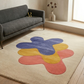 Colorful abstract rug on a wooden floor with a gray sofa in a room.
