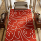 Red patterned rug with white designs in a room with furniture and decor.