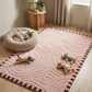 Pink patterned rug with toys and a cat bed in a room.