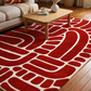 Red patterned rug on a wooden floor with a coffee table and sofa in the background.