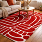 Living room with a red and white patterned rug, beige sofa, and wooden coffee table.
