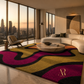 A large area rug with a bold wavy abstract pattern in magenta, mustard yellow, black, and orange, styled in a modern living room with a curved white sofa and large floor-to-ceiling windows.