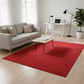 Modern living room with a red rug, gray sofa, and a desk.