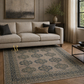 Beige sectional sofa in a living room with a patterned rug and decorative elements.