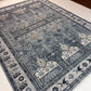 Close-up of a patterned blue rug with intricate designs on a white surface.