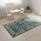 Children's play area with a blue patterned rug, table, and chairs in a bright room.