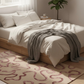 Neatly made bed with white bedding and a gray throw blanket in a bedroom setting.