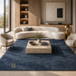 A modern living room featuring a large navy blue textured area rug under a curved cream boucle sofa, with two matching armchairs, a stone coffee table, and warm wood cabinetry in the background.