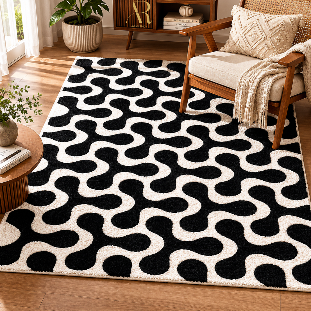 A black and off-white area rug with a bold, repeating wavy pattern, styled in a bright, modern living room next to a wooden armchair and a small round table.