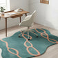 Teal and pink patterned rug on a wooden floor with a white chair and desk.