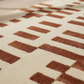 Close-up of a patterned rug with brown and beige colors.