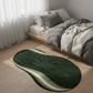 Green and white wavy rug on a wooden floor in a bedroom with a bed and curtains.
