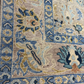 Close-up of a patterned rug with blue, beige, and brown colors.