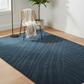 Blue patterned rug on a wooden floor with a chair and plant in the background