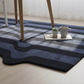 Blue and black striped rug on a light wooden floor with a small table and items on it.