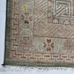 Close-up of a patterned rug with geometric and floral designs on a light background.