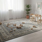 Children's play area with toys on a patterned rug in a bright room.
