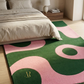 Decorative pink and green rug with circular patterns in a bedroom setting.