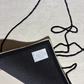 Black book with a label on a light gray surface with black abstract line art.