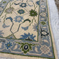 Close-up of a patterned rug with blue and green designs on a beige background