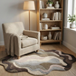 Beige armchair with a blanket on a wavy patterned rug in a cozy living room.