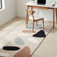 Colorful abstract rug on a wooden floor with a desk and chair in the background.