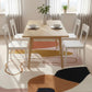 Dining area with a wooden table and white chairs on a colorful rug.