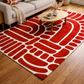 Red and white patterned rug on a wooden floor with a coffee table and sofa in the background.