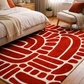 Red patterned rug on a wooden floor in a bedroom setting