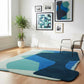 Modern living room with a geometric patterned rug, chair, and framed artwork.