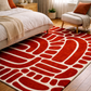 Red and beige patterned rug in a bedroom setting with furniture and decor.